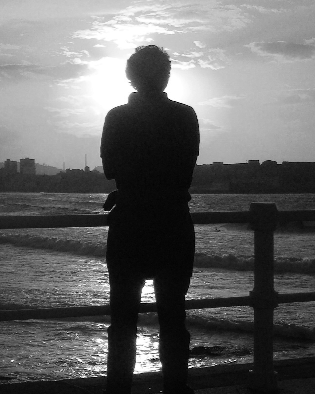 A silhouetted figure looking across the water in the evening light