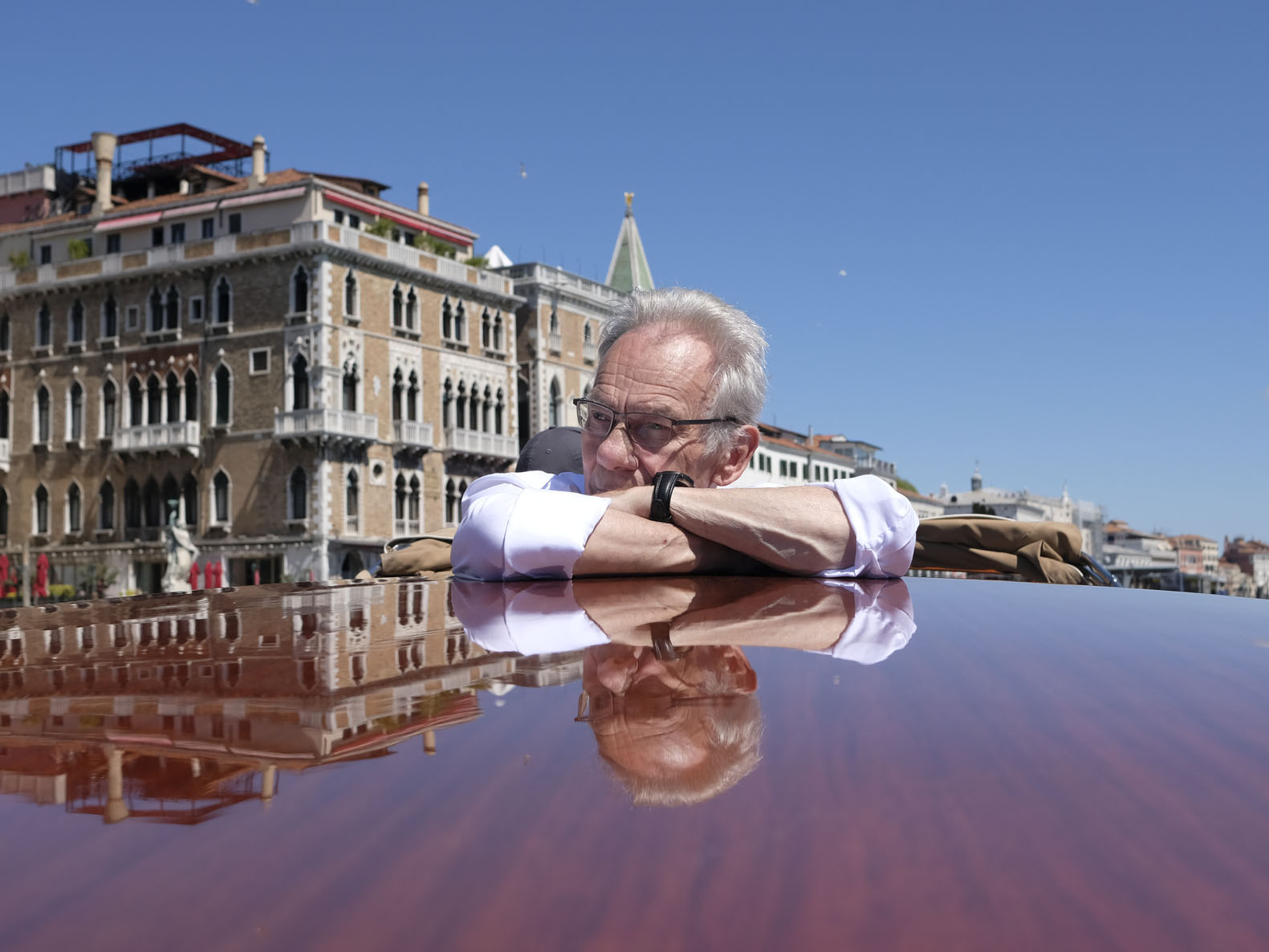 John Myatt resting his arms on the polished roof of a boat in Venice