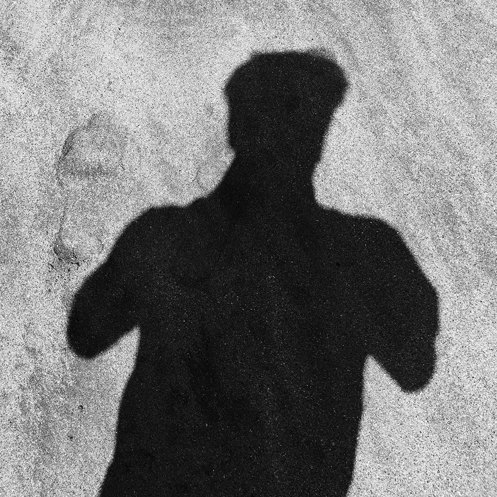 A black-and-white shadow portrait on a textured wall