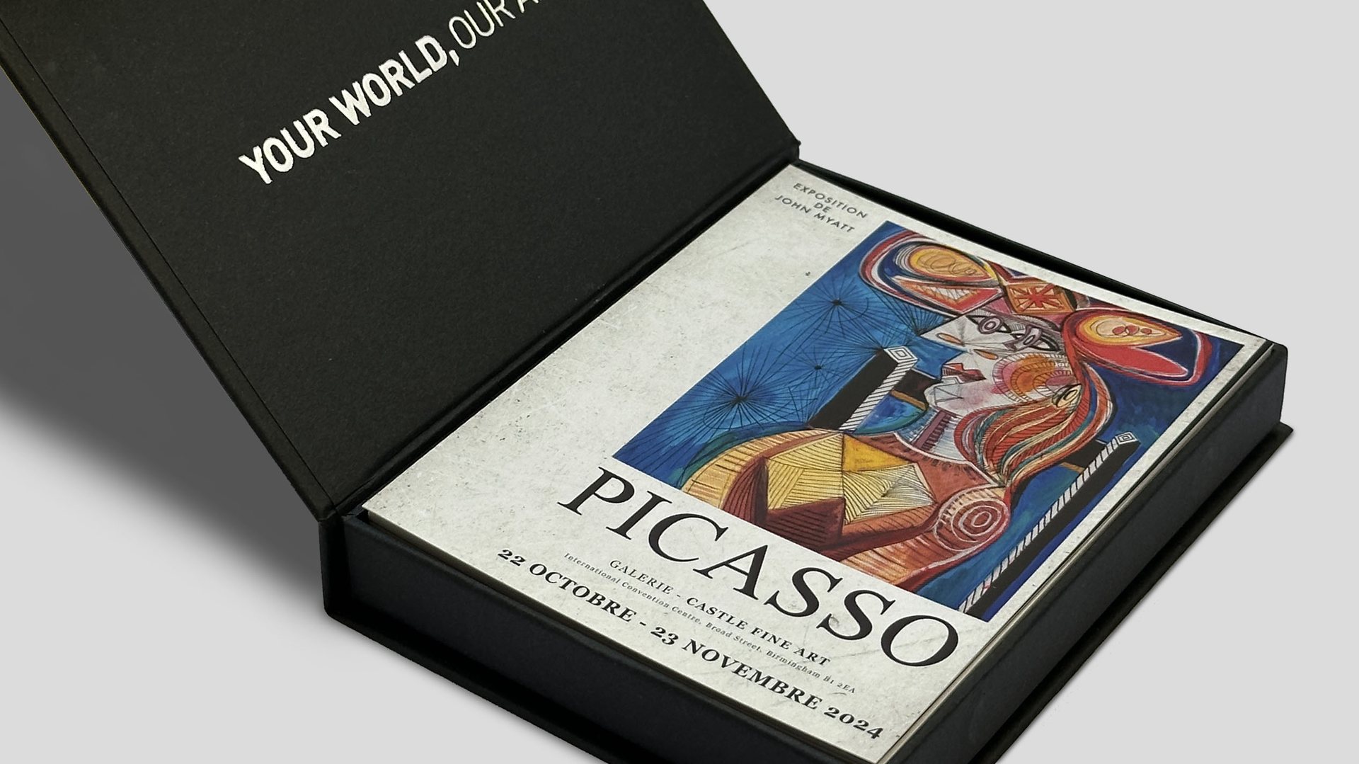 Black presentation box holding a Picasso exhibition poster, with the words Your World, Our Art