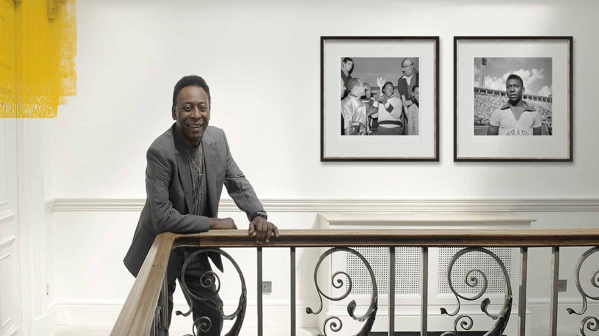 Pelé leaning on a banister beneath two framed photographs