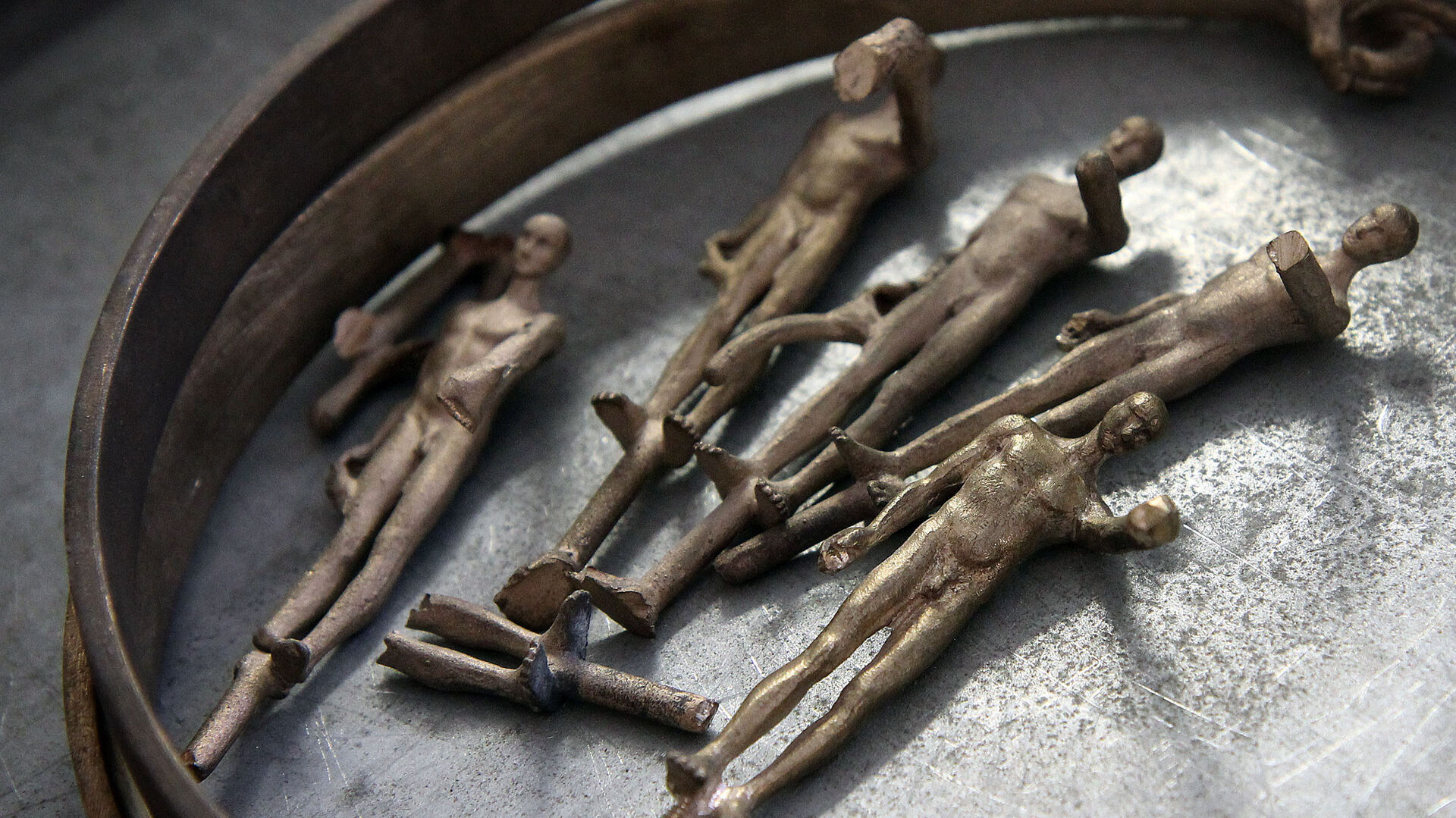 Bronze maquettes of human figures laid out on a foundry workbench
